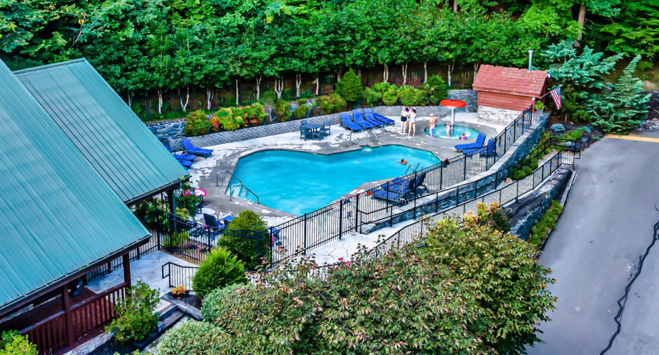 Kids enjoying a pool at one of the best neighborhoods in Gatlinburg for families, surrounded by tall trees and a relaxing cabin setting.