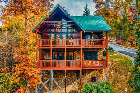 Log cabin rental in Gatlinburg TN surrounded by autumn foliage, featuring multiple decks and scenic mountain views.